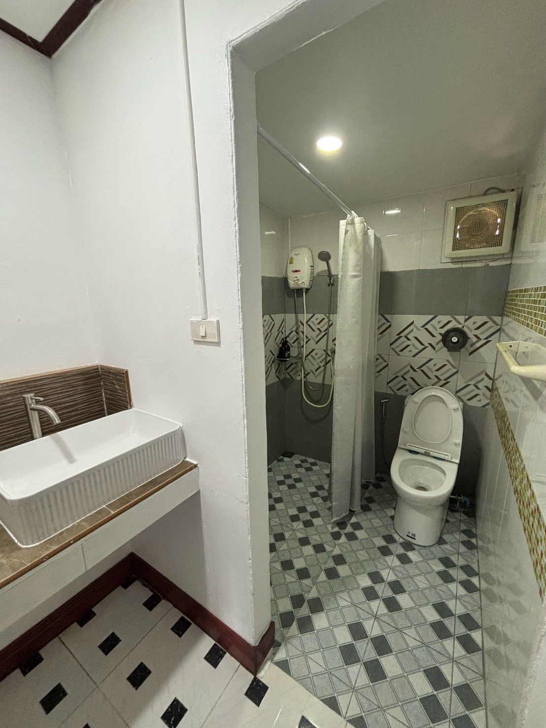 A bathroom with a sink, toilet, and shower area.