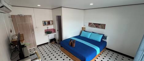 Un dormitorio con cama, lavamanos, espejo y puerta.