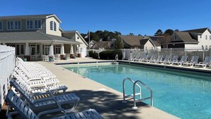 A swimming pool with lounge chairs and a building in the background.