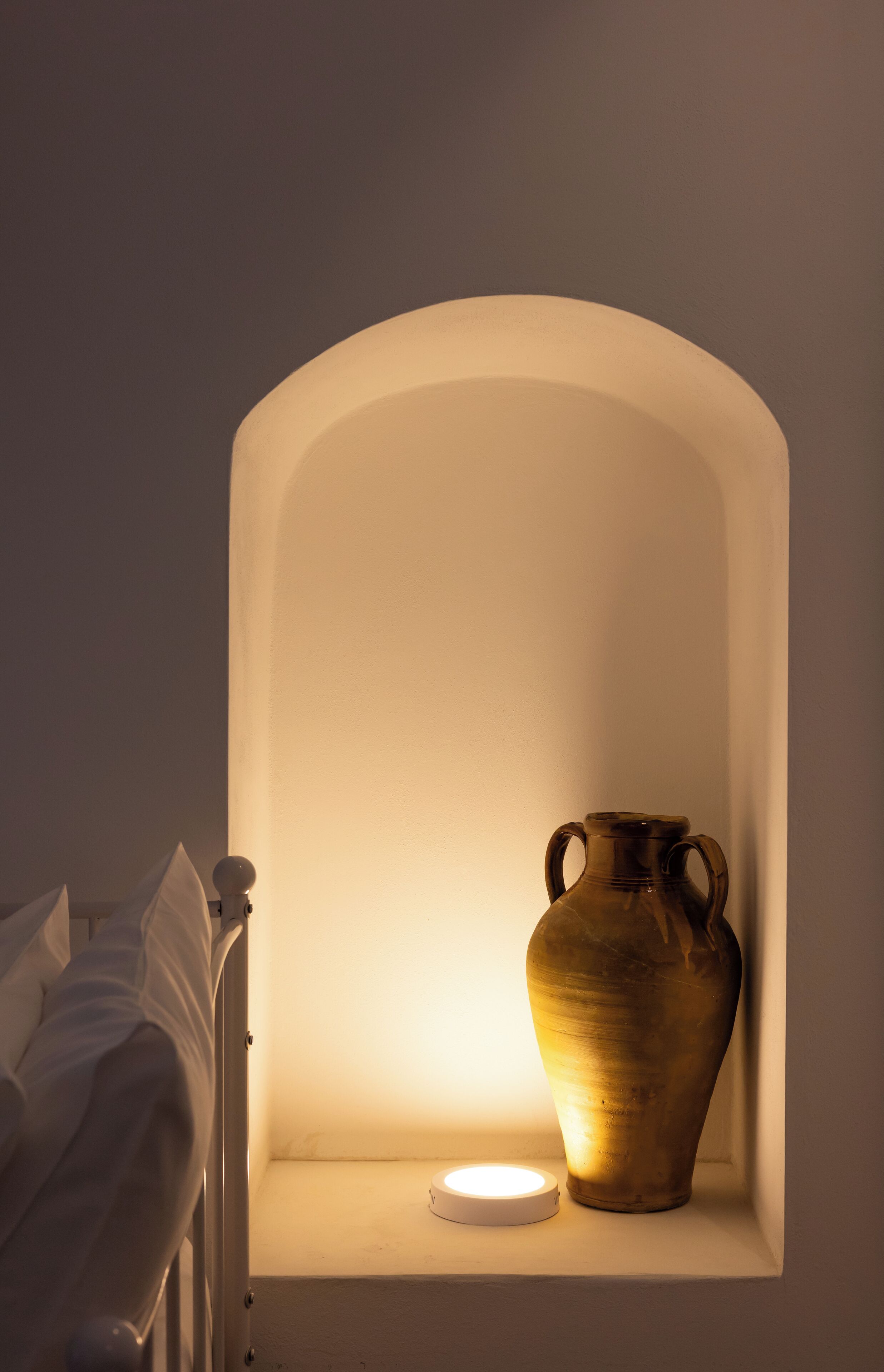 A bedside table with a vase and a lamp.