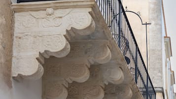 Een gevel met een decoratieve stenen balustrade en een zwarte metalen hekwerk.