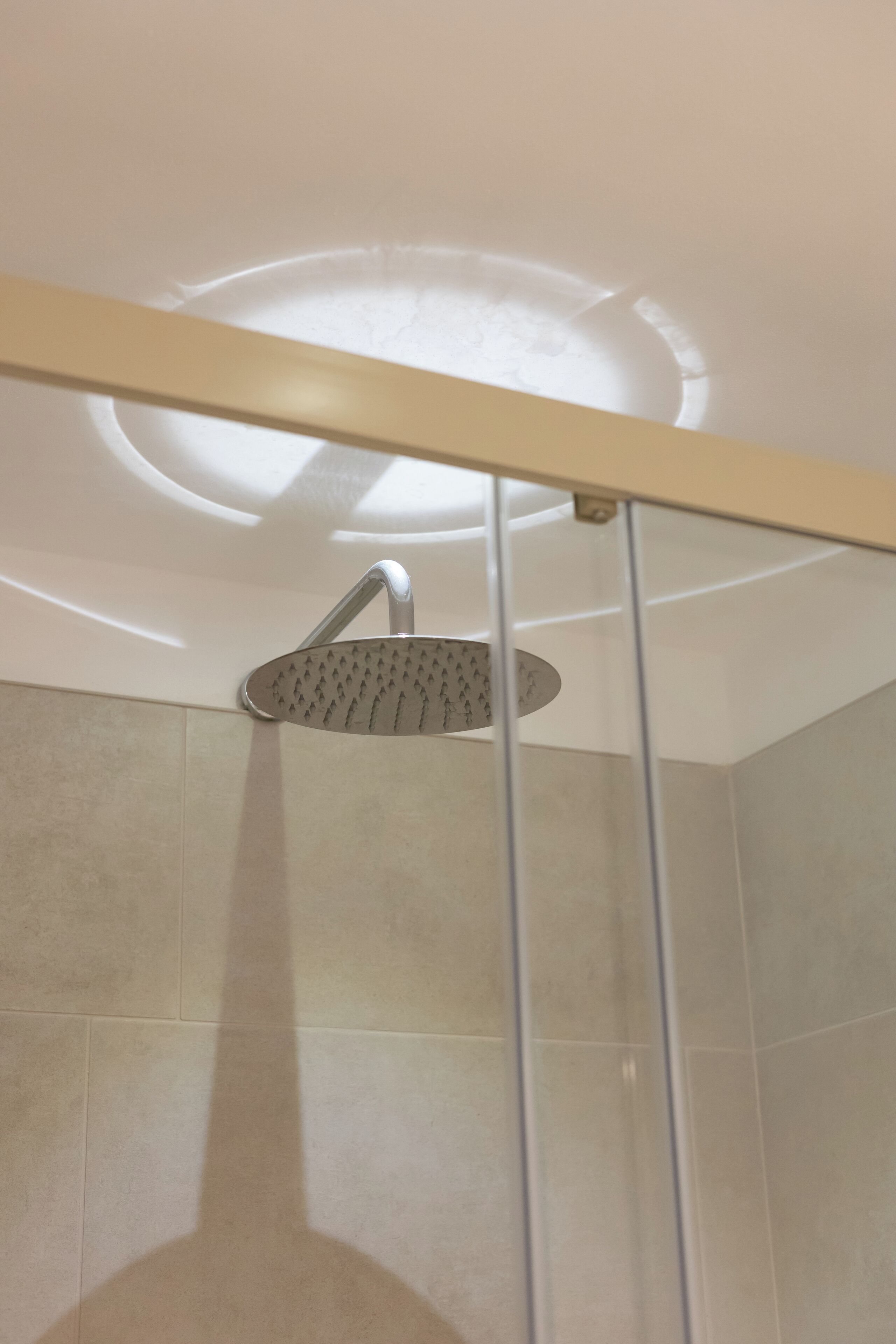 A shower with a modern design, including a curved showerhead and a glass partition.