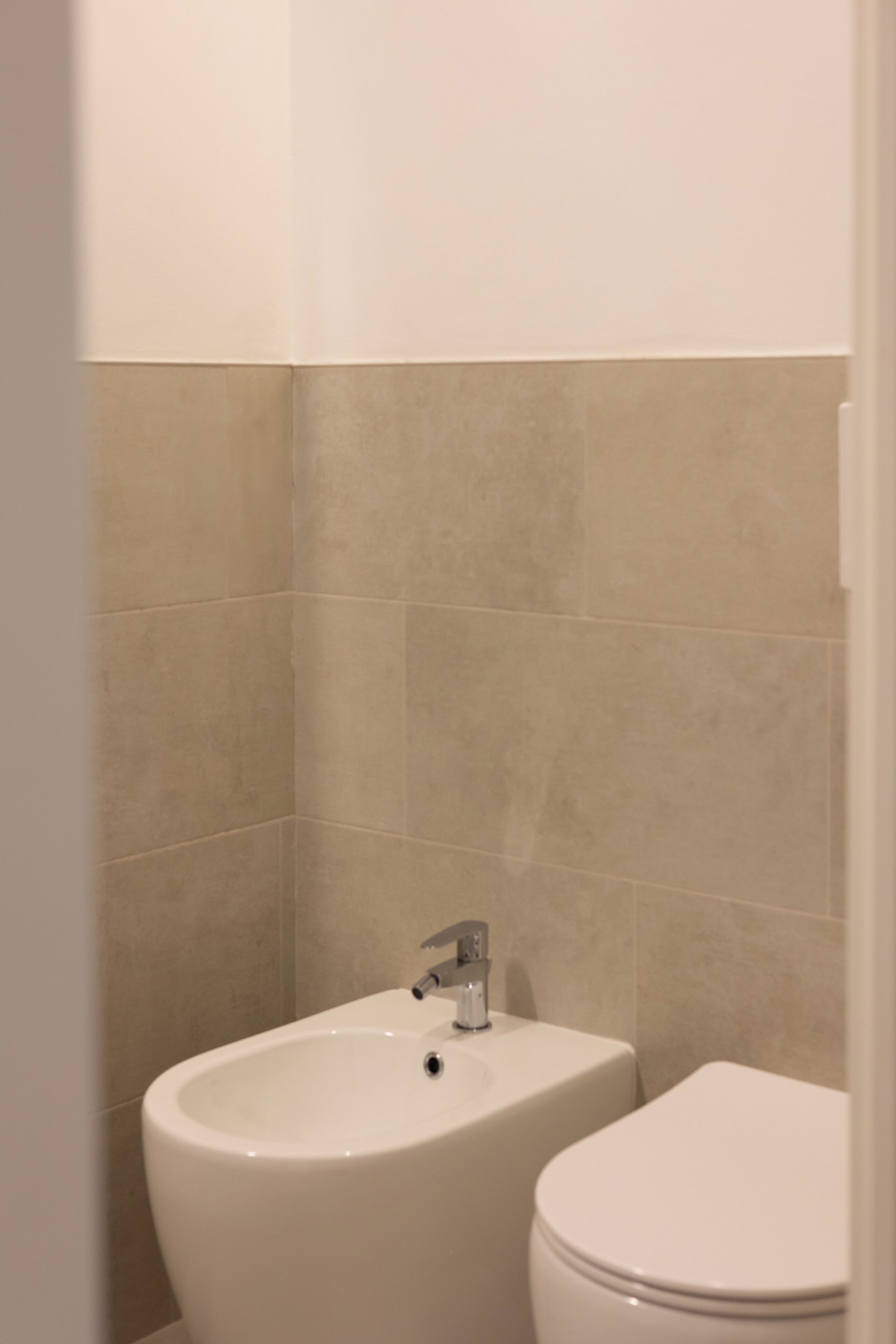 A bathroom with a bidet, a toilet, and a sink.