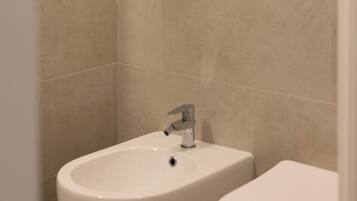 A bathroom with a bidet, a toilet, and a sink.