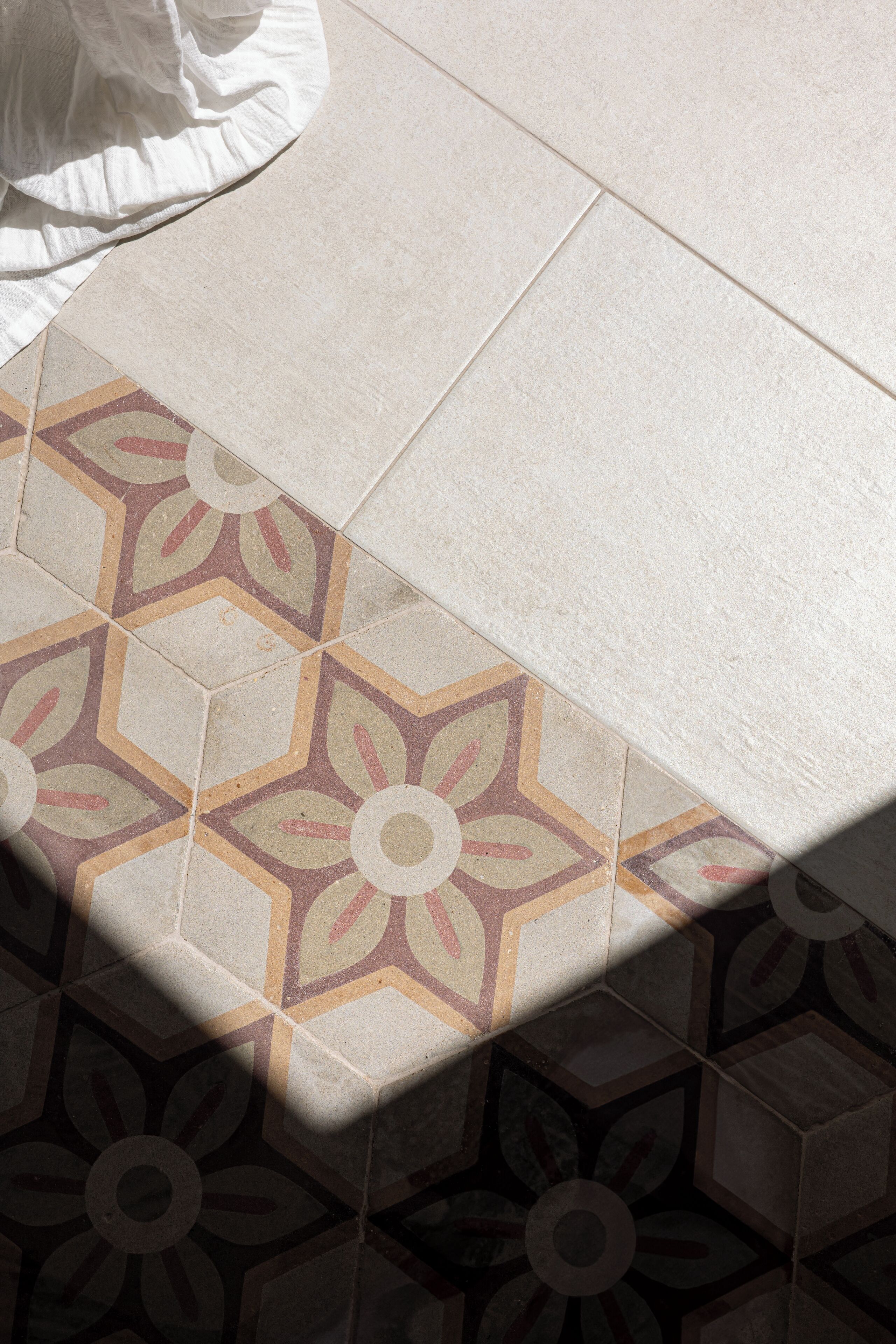 Um close-up de um chão de azulejos com padrões geométricos e florais.