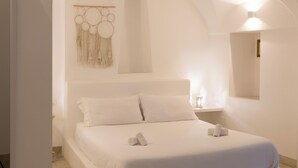 A minimalist bedroom with a large bed, a bedside table, and a wall-mounted light fixture. - Donna Veneranda (Vieste)