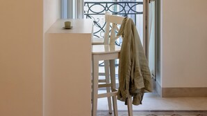 A room with a white table and chair, a balcony door, and a patterned floor.