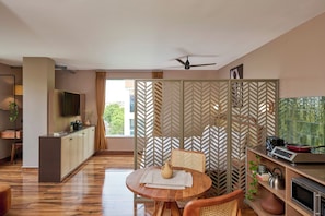 A modern kitchen with a dining area, a television, and a ceiling fan.