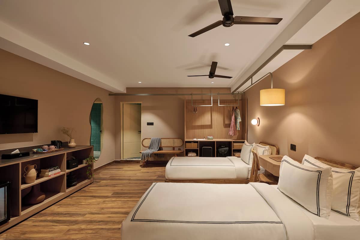A hotel room with two beds, a TV, a desk, and a wardrobe.