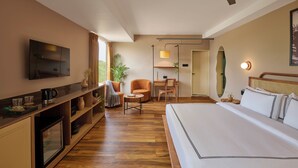 A hotel room with a bed, a desk, a chair, a television, and a ceiling fan. - Minimalist - The Varanasi Edit (Varanasi)
