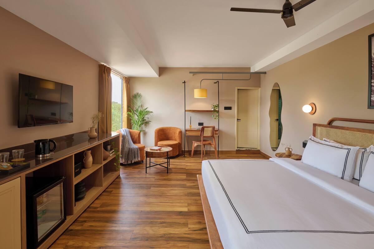 A hotel room with a bed, a desk, a chair, a television, and a ceiling fan.