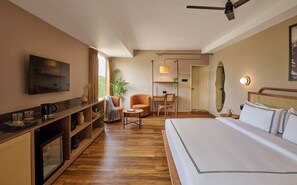 A hotel room with a bed, a desk, a chair, a television, and a ceiling fan.