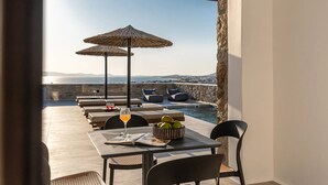 Une terrasse dotée d’une piscine, de chaises longues et de parasols, offrant une vue panoramique.