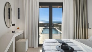 Une chambre avec un grand lit, une vue sur la piscine et l’océan, et une porte-fenêtre coulissante.
