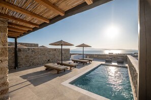 A poolside area with lounge chairs and umbrellas, overlooking a body of water and a distant landscape. - Lithia Exclusive Villas (Naxos)