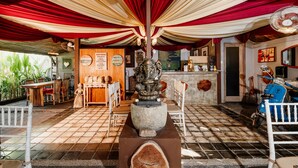 A restaurant with a wooden table and chairs, a statue, and a blue scooter. - Kemala Living Sanur (Denpasar)
