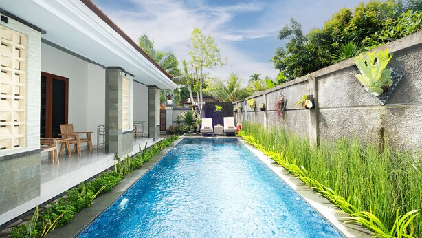 A swimming pool with a stone wall on one side and a white building on the other. - Kemala Living Sanur (Denpasar)