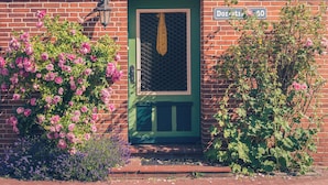 A brick building with a green door, a window with a yellow curtain, and a sign reading "Dorchester 40".