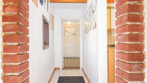 A hallway with brick walls, framed pictures, and a tiled floor.