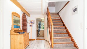 A hallway with a wooden dresser, a mirror, a coat rack, and a staircase with wooden railings.
