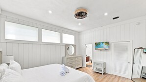 Une chambre à coucher avec un grand lit, une commode, un miroir et un tableau accroché au mur.