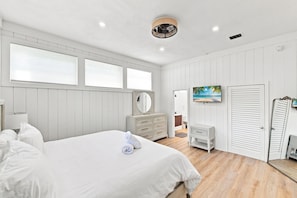 Een slaapkamer met een groot bed, een dressoir, een spiegel en een schilderij aan de muur.