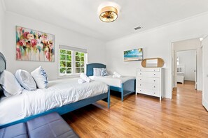 Un dormitorio con cama, escritorio, silla y ventana.