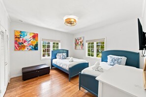 A hotel room with two beds, a bench, and artwork on the walls.