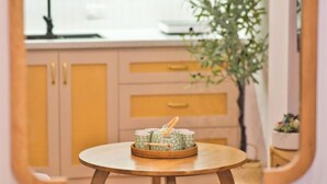 Ein runder Holztisch mit einer Platte dekorativer Gegenstände in einem Raum mit hellen Wänden und Holzschränken.