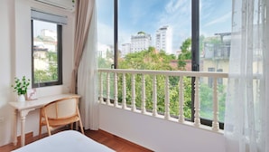 Ein Schlafzimmer mit großem Fenster, Schreibtisch, Stuhl und Bett.