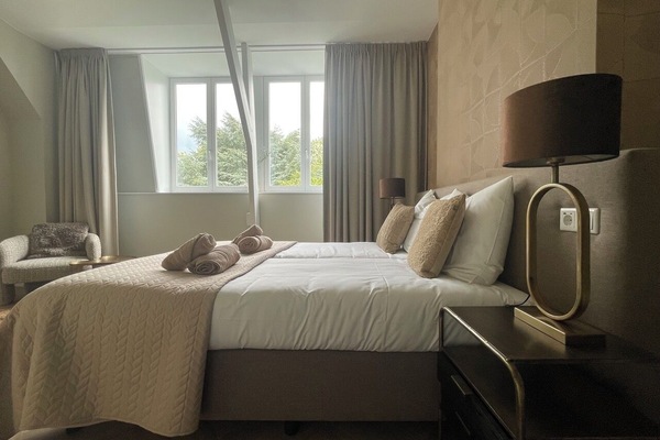 Serene bedroom with natural light, warm beige tones, and a soft double bed — ideal for unwinding after a day in the city or nature.