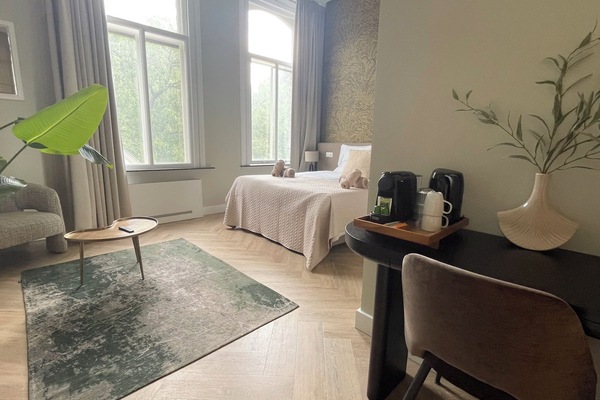 Spacious bedroom at Bed en Koffie Stationsstraat with king-size bed, TV, and serene garden views.