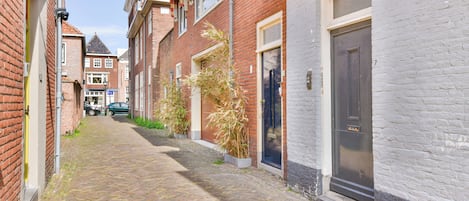 A narrow cobblestone street lined with traditional brick buildings, featuring a mix of residential and commercial properties.