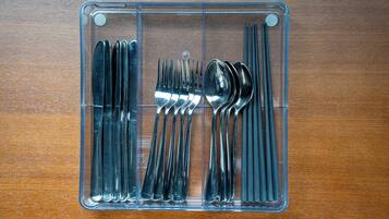 A clear plastic storage organizer with utensils neatly arranged inside.
