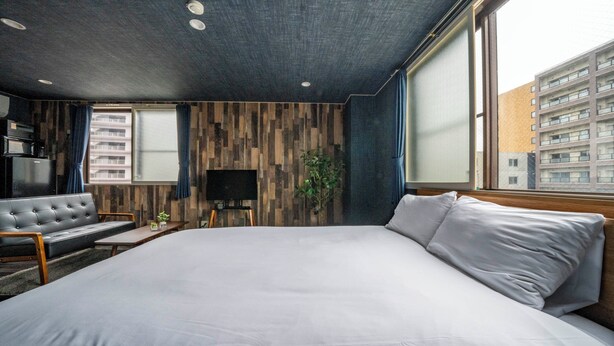 Una habitación de hotel moderna con una cama grande, televisión de pantalla plana, sofá y mesa de comedor.