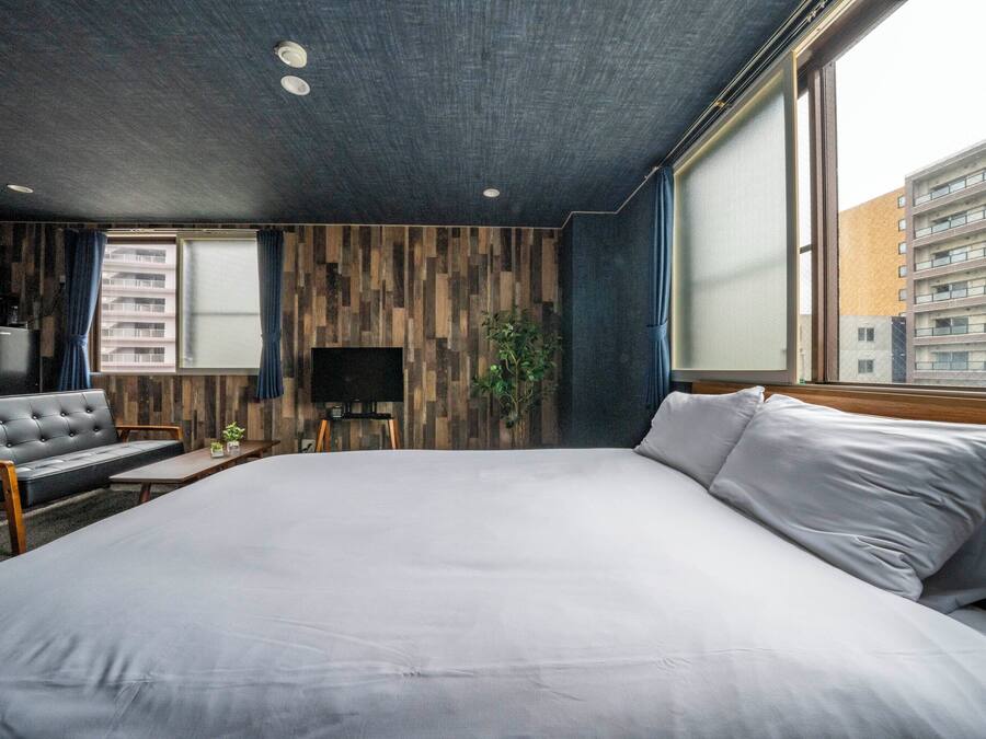 Een moderne hotelkamer met een groot bed, een flatscreen televisie, een bank en een eettafel.
