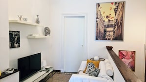 A modern living room with a flat-screen TV, white sofa, and artwork on the walls. - Relax in this quiet space just a stone's throw from Tesoriera Park. (Torino)
