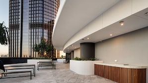 A modern reception area with a curved reception desk, seating area, and a view of a tall building.