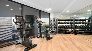 A gym with cardio machines, weightlifting equipment, and a view of the city.