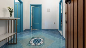 A hallway with blue doors, a tiled floor with a compass design, and a small table with a vase of flowers. - Domus Vittorio double room with balcony and sea view  (Gaeta)