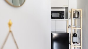 A compact kitchen with a black refrigerator, a microwave, and a coffee maker on a wooden shelf. - Domus Vittorio double room with balcony and sea view  (Gaeta)