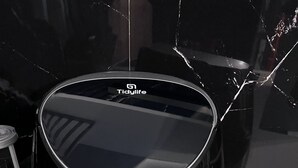Una tetera eléctrica negra con tapa transparente y panel de control sobre una encimera blanca.