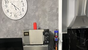 Una cocina con un refrigerador de doble puerta, un reloj de pared, un horno empotrado y un microondas.
