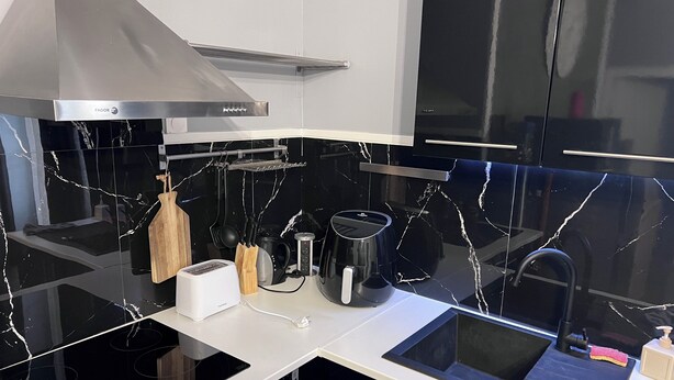 Una cocina moderna con encimeras de mármol negro, electrodomésticos de acero inoxidable y una campana extractora.