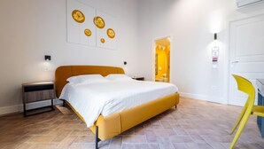 A bedroom with a bed, a nightstand, a chair, and a wall with artwork. - Guest House Le Sei Porte   Porta Elina (Salerno)