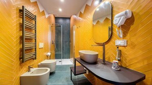 A modern bathroom with a herringbone-patterned wall, a freestanding bathtub, a sink with a large basin, a mirror with a hairdryer, and a shower area. - Guest House Le Sei Porte   Porta Elina (Salerno)