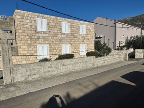Um edifício de pedra com várias janelas e uma rua pavimentada na frente.