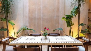 Un espace repas comprenant une table et des chaises, entouré de plantes en pot.
