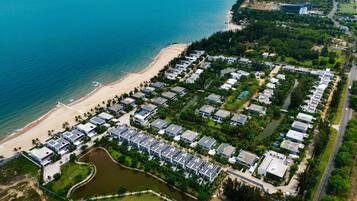 Vista aérea de um resort costeiro com vários edifícios, uma praia e um rio.