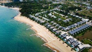 Vista aérea de una zona residencial costera con playa, casas e paneles solares.